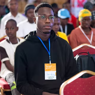 Yves in the audience at a conference, wearing a Lightning Speaker lanyard