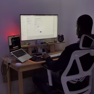 Yves from behind at his desk, working across a monitor and a laptop